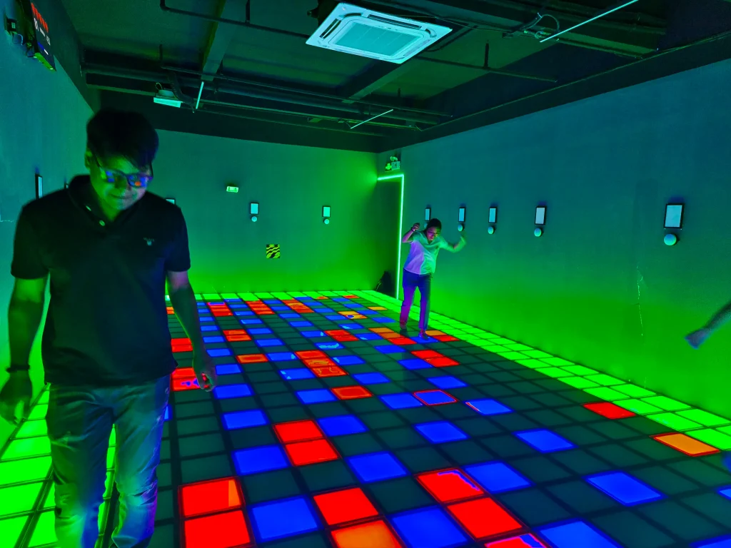 Multiple players leaping across a multi-colored LED grid floor